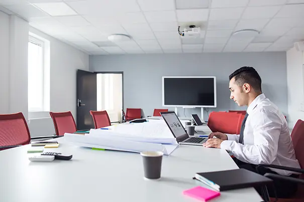 AV technician running a diagnostic check in a meeting room with an HVAC ceiling diffuser visible