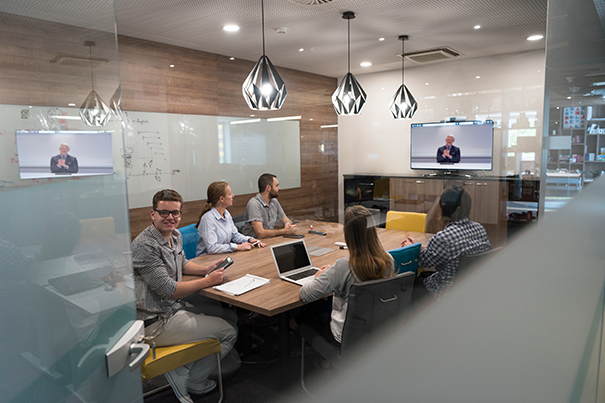 Executive board room designed for hybrid video conferencing with displays and camera at the head of the table