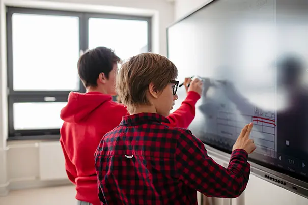 Students and a trainer using an interactive display in a hybrid-enabled smart classroom