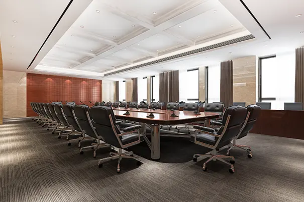 Large enterprise conference room with U-shaped table and dual displays showing a remote participant