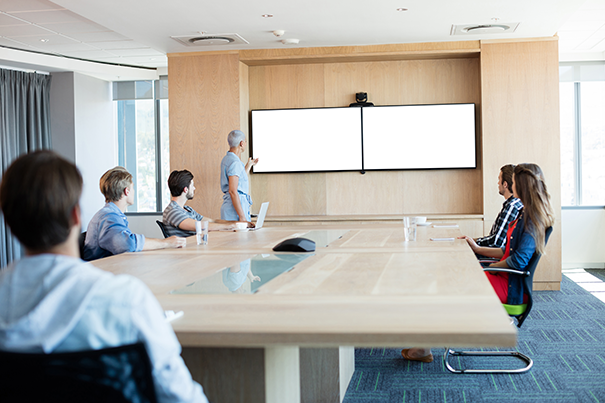 Auto-framing conferencing camera positioned for optimal sightlines in a hybrid meeting room
